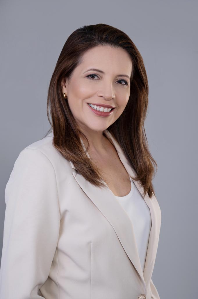 Luzimar Collares sorrindo, de blazer creme, em retrato de estúdio